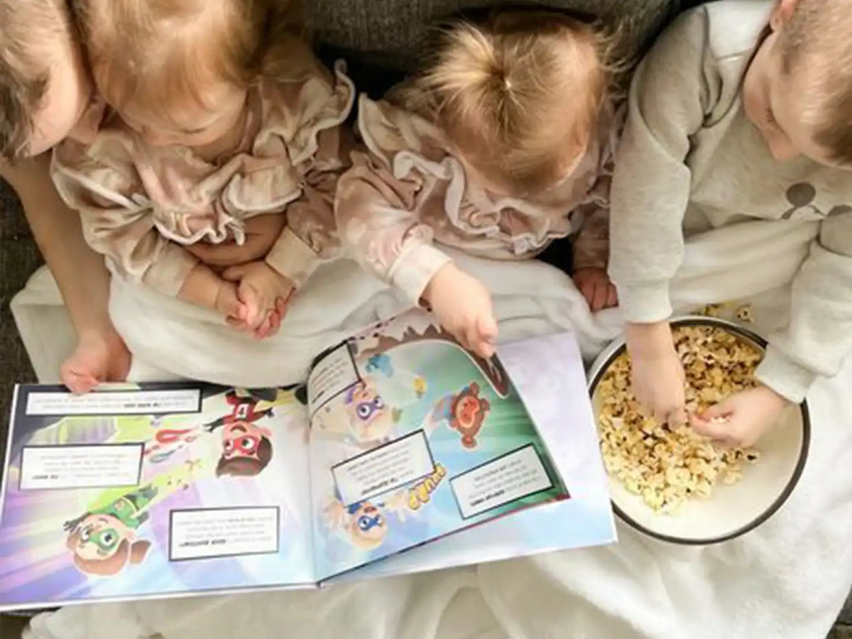 4 Kinder essen Popcorn und lesen ihr persönliches Buch von Hurra Helden. 