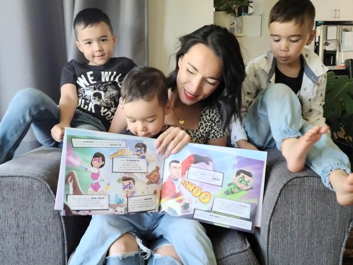 Eine Mutter mit drei Söhnen schauen sich ihr personalisiertes Buch von Hurra Helden. 