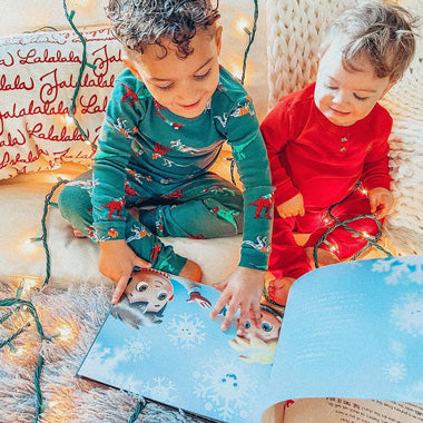 Zwei Kinder blättern in ihrem eigenen personalisierten Buch, das über Weihnachten und ihrer Verbindung handelt.