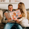 Mann und Frau sitzen auf einer Couch und halten ein personalisiertes Buch der Liebe in der Hand.	