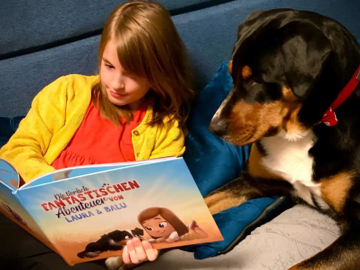 Ein kleines Mädchen lächelt über die Illustrationen ihres neuen personalisierten Buches, das nur für sie und ihren Hund  gemacht wurde.			
