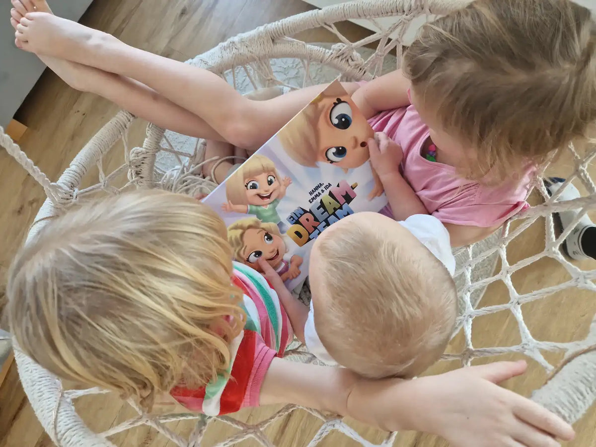 Dreis Kinder in einer Schaukel lesen ihr personalisiertes Buch für Geschwister. 