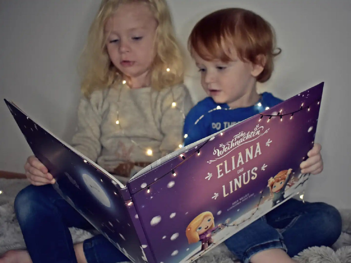 Ein Bruder und Schwester lesen ihr personalisiertes Buch zu Weihnachten von Hurra Helden.