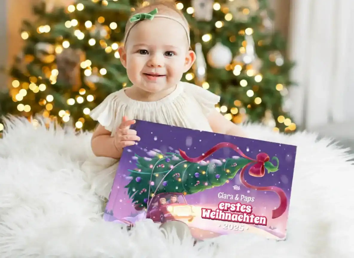Baby hält das personalisierte Buch „Clara & Paps – Erstes Weihnachten 2025“ vor einem Weihnachtsbaum.