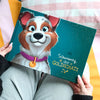 Person hält ein personalisiertes Premium-Hundebuch mit dem Titel „Sammy, der GOLDSCHATZ“ mit einem fröhlich gezeichneten Hund auf dem Cover.